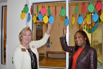 Development Director Carol Harrison and Marketing Director Ashley Strickland with the pledge light bulbs that are hanging in the lobby of the house.