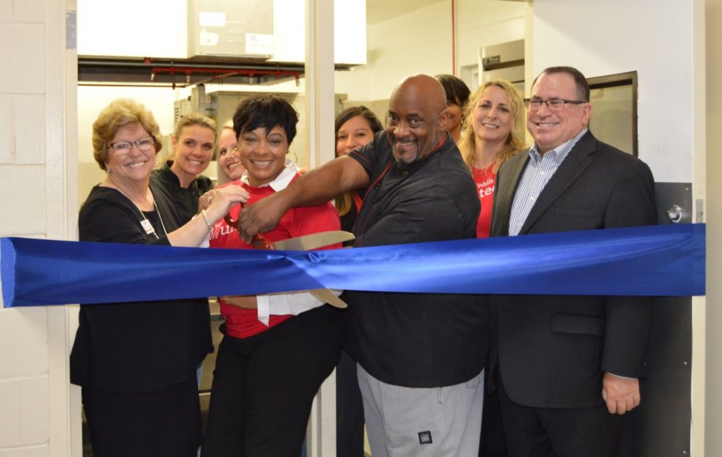 Cutting the ribbon to unveil the new Wells Fargo Community Kitchen were Penny Kievet, executive director of the City Rescue Mission; Cheryl Clark, City Rescue Mission chef; Heather Fincher, Valerie Jenkins, and Monica Smolder of Wells Fargo; CRM Chef Ron Scott; Keri Michelle Shaw and Michelle Berman of Wells Fargo; Mark Middlebrook, regional manager, north and central Florida for Wells Fargo Investment and Fiduciary Services