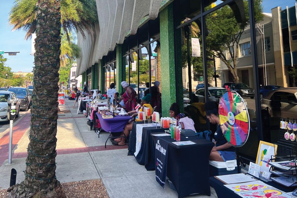 photo of people at display tables outside of library
